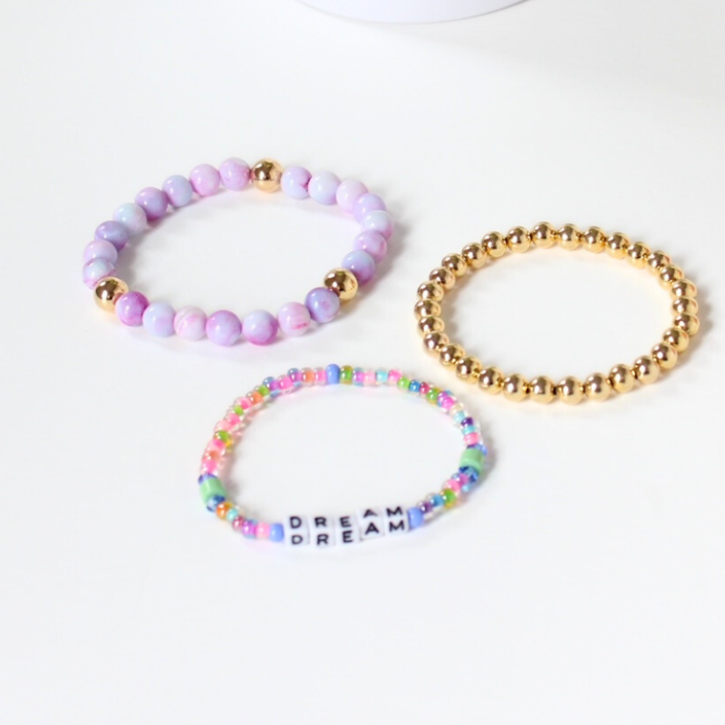 Set of 3 bracelets. Purple opal gemstones beaded bracelet is the star of this bracelet. This bracelet is designed with gold filled round beads and a dainty rainbow beaded white cubed letter beaded bracelet.