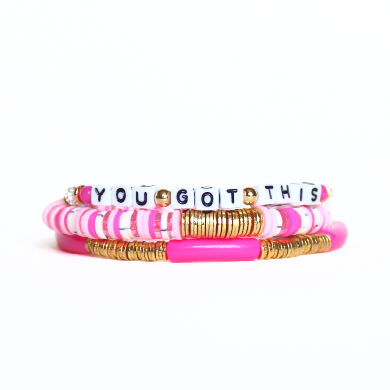 Pink beaded breast cancer awareness bracelet set. This very pink 3-piece bracelet set is curated with pink acrylic bangle, clear round quartz beads, pink beads and word beaded bracelet. Proceeds will be donated to the Susan G. Komen Foundation.