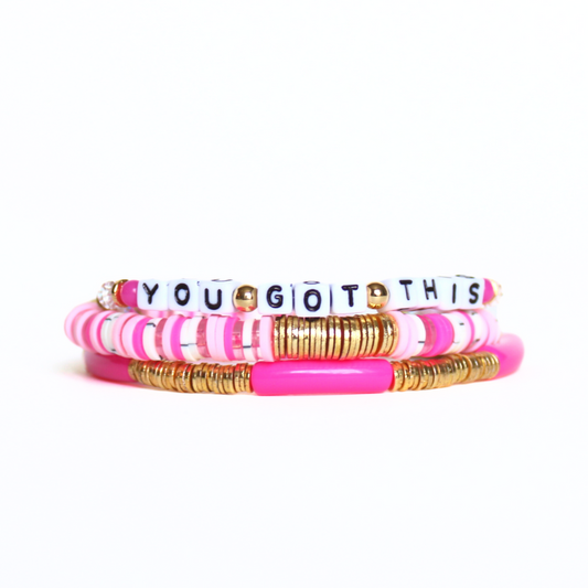Pink beaded breast cancer awareness bracelet set. This very pink 3-piece bracelet set is curated with pink acrylic bangle, clear round quartz beads, pink beads and word beaded bracelet. Proceeds will be donated to the Susan G. Komen Foundation.