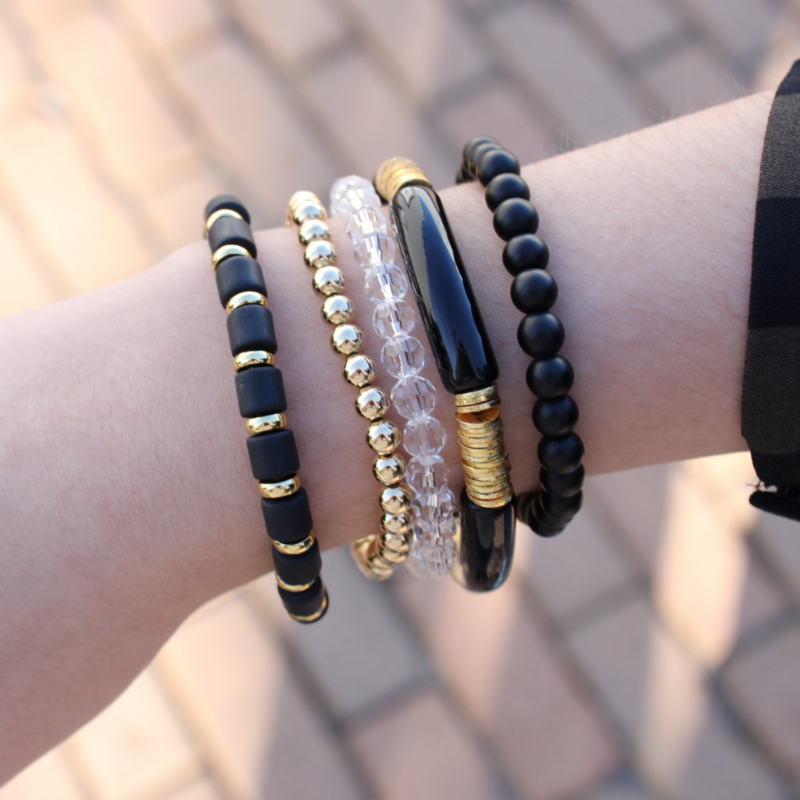5-piece black beaded stretch bracelet set. is designed with 18k gold-filled beads. Also designed with black polymer clay beads, clear and black glass beads and black acrylic bangles. This stack is perfect for that night out with the girls or that special someone. Dress up any dress or pant suit with this classic black statement piece.