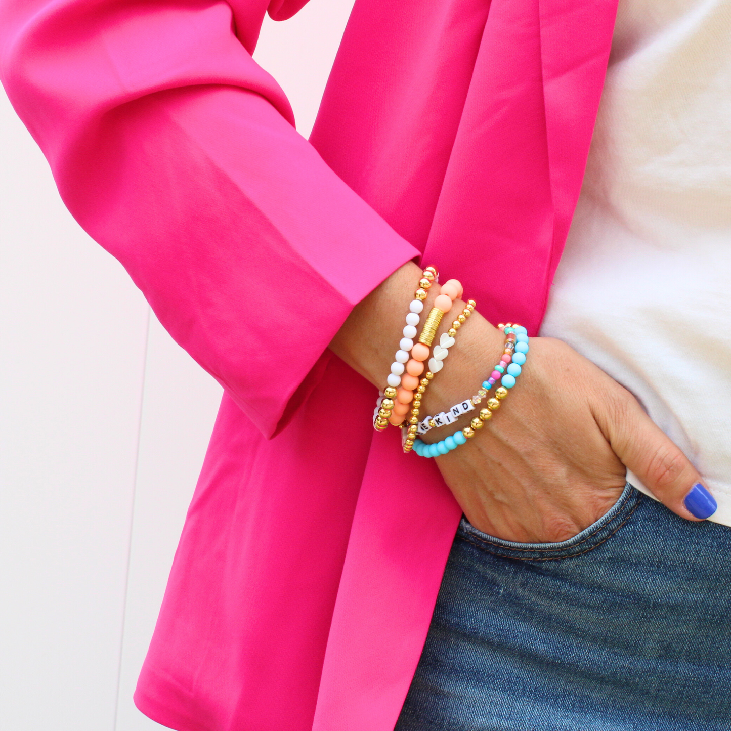 5-piece stacking bracelet with peach and blue acrylic beads. White acrylic and white mother of pearl heart charms are accent with gold filled round beads. A dainty letter bead with rainbow seed beads complete the set.