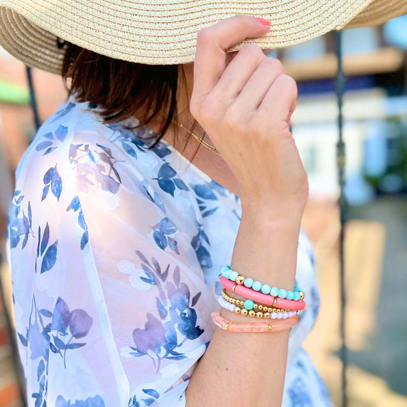 Model wearing 3-peice beach inspired stack. Designed with peach marble 8mm skinny acrylic bamboo tubes with gold plated flats. This stack also is designed with 8mm blue opal beaded bracelet with gold filled beads and a 5mm gold filled beaded bracelet accented with white round acrylic beads.