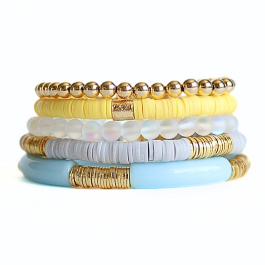 This bracelet set comes with five bracelets. One 5mm 18k gold filled beaded bracelet. One bright yellow disc polymer clay beaded bracelet featuring a gold plated cylinder bead. One 6mm frosted mermaid beaded bracelet. One light gray polymer clay beaded bracelet with gold plated flat beads. One light blue acrylic bangle bracelet with gold plated flat beads