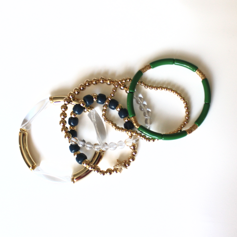 5-Piece 18k gold beaded stretch bracelet with clear round natural Brazilian quartz gemstones. 2 bracelets have green, clear and gold acrylic bangles. This set is also designed with ocean blue forte gemstone beads.