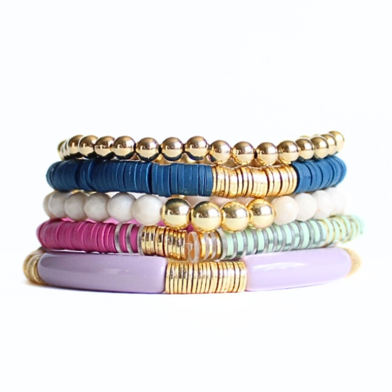 This 5-piece blue and purple beaded stretch bracelet set is the perfect statement piece. With its warm colors, it is designed with 18K gold filled beads and faceted natural coral river stone. Also designed with blue and purple polymer clay beads and a purple acrylic bangle.