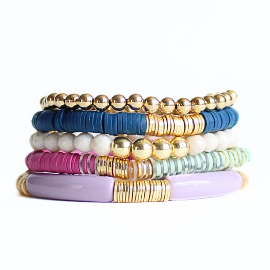 This 5-piece blue and purple beaded stretch bracelet set is the perfect statement piece. With its warm colors, it is designed with 18K gold filled beads and faceted natural coral river stone. Also designed with blue and purple polymer clay beads and a purple acrylic bangle.