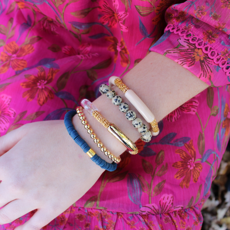 This 5-piece blue beaded stretch bracelet set is the perfect statement piece. With its neutral colors, it is designed with 18K gold filled beads, blue polymer clay beads and jasper beads. The clear, gold and cream acrylic bangles give it a modern look.