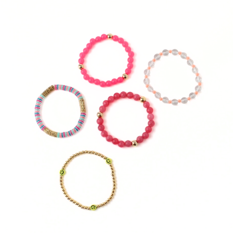 5-piece pink beaded bracelet stack. Designed with bright pink acrylic round beads accented with gold filled round beads. Clear quartz round beaded bracelet is adorned wth 4mm peach acrylic beads. Rainbow polymer clay beads and a gold and smiley face beaded bracelet add a playful side.