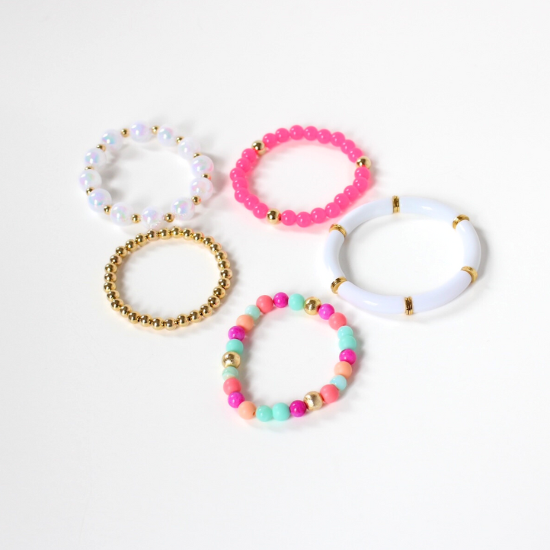 Set of 5 bracelets. The Santorini bracelet stack has white tubed and round iridescent acrylic beads. A bright pink acrylic beaded bracelet adds color and attitude. This bracelet has a stunning bracelet mixed with pink and blue opal beads.