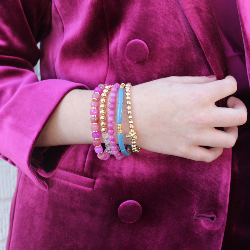 5-Piece purple beaded stretch bracelet set with 18k gold filled beads. The two gold beaded bracelets are designed with clear Brazilian quartz beads and a 14k gold forte charm. The two purple beaded bracelets are designed with forte gemstone beads and jade round beads. The skinny blue acrylic bangle adds the perfect touch.