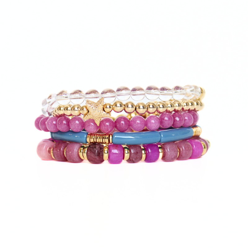 5-Piece purple beaded stretch bracelet set with 18k gold filled beads. The two gold beaded bracelets are designed with clear Brazilian quartz beads and a 14k gold forte charm. The two purple beaded bracelets are designed with forte gemstone beads and jade round beads. The skinny blue acrylic bangle adds the perfect touch.