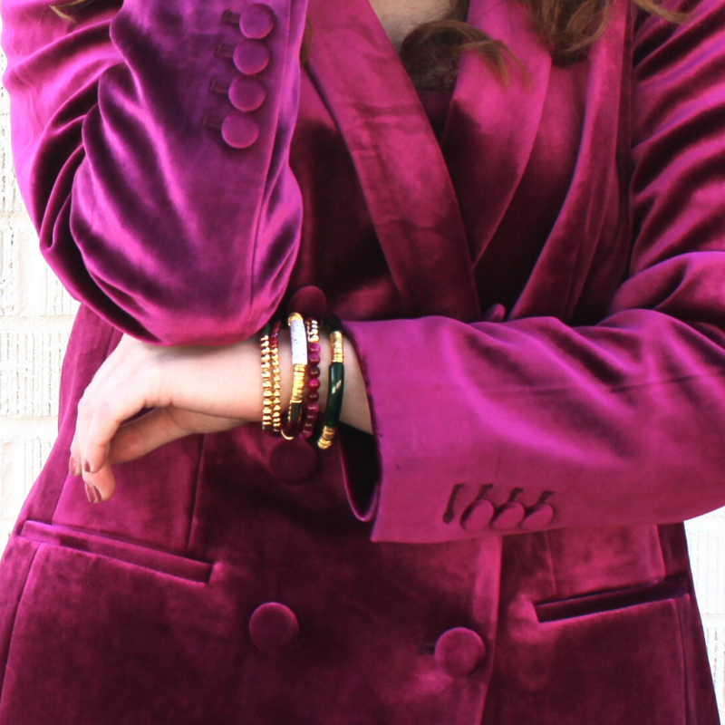 Red and green 5-piece 18K gold beaded stretch bracelet set designed with glass beads, red seed beads and natural fuchsia Tigers eye beads. Two bracelets are designed with white speckled and green acrylic bangles with gold flat beads.