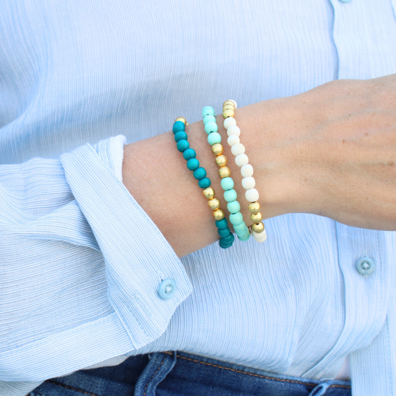 Model is wearing the 3 piece tropical inspired beaded bracelet stack made up of wooden beads for a unique texture.
