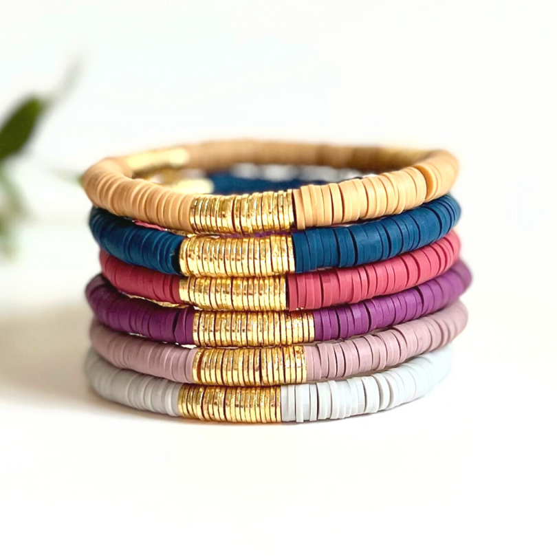 a variety of polymer clay beaded bracelets with gold plated flat beads
