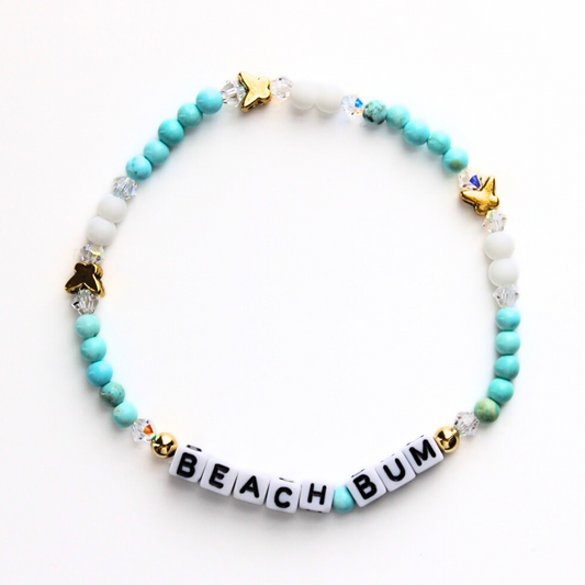 Dainty beachy stretch word bracelet. Designed with white cubed letter beads, blue 4mm jasper beads, 4mm white acrylic beads and gold plated butterfly charms. Personalize letter beads with name, initials or any inspirational word.
