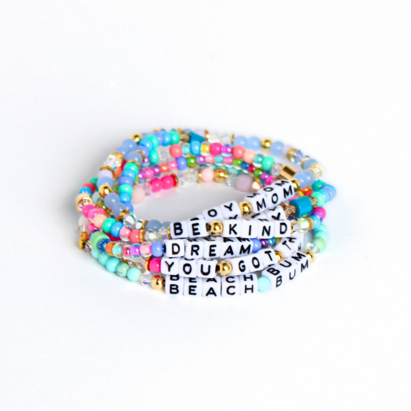 Stack of colorful seed bead letter bead bracelets.