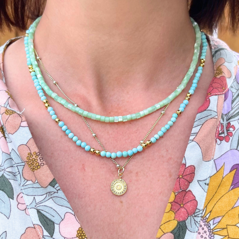 Model wearing green opal beaded layering necklace. The green opal necklace is layering with a blue jasper and satellite gold chain with coin pendant.