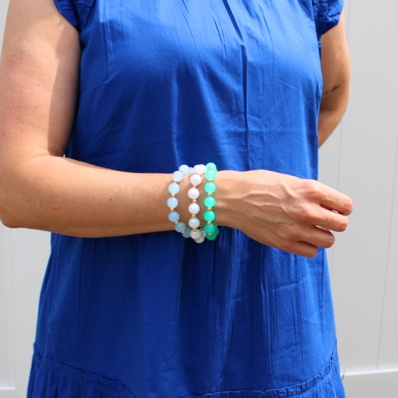 Model wearing 3-peice chunky acrylic beaded bracelet set. Blue, green and white 12mm large acrylic beaded bracelets with 5mm gold-filled beads.