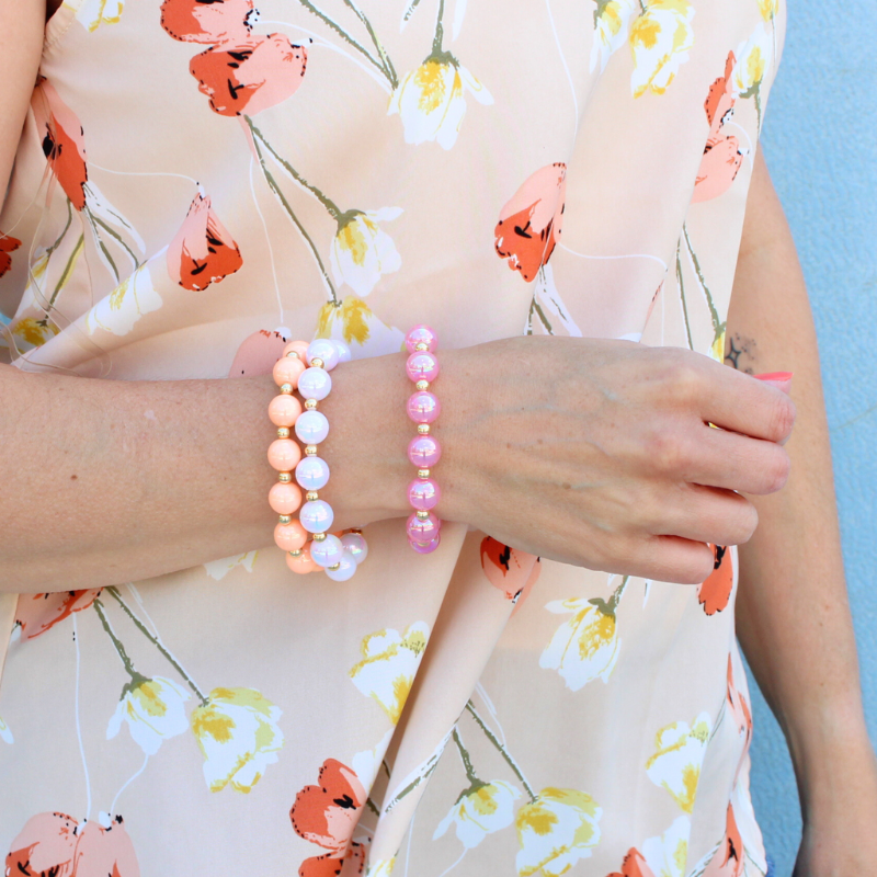 Model wearing 3-piece chunky acrylic beaded bracelet set. Designed with 12mm pink, white and peach iridescent acrylic beads. Between each acrylic bead is a 5mm 18k gold filled round beads.