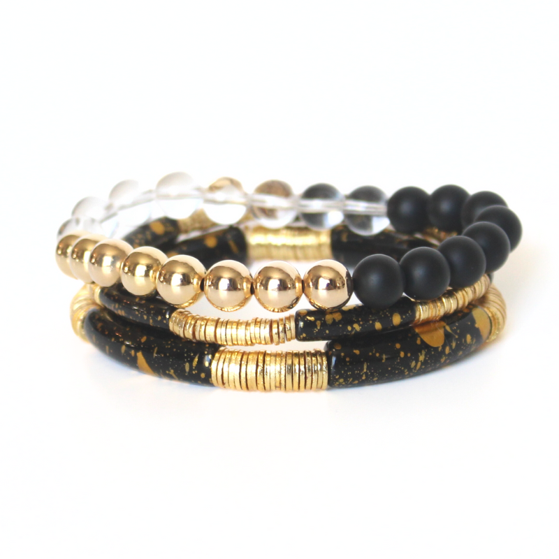 This 3-piece black beaded stretch bracelet set is the perfect statement piece. With its classic colors, this bracelet set is designed with 18K gold filled beads, white crackled beads, and black acrylic bangles.