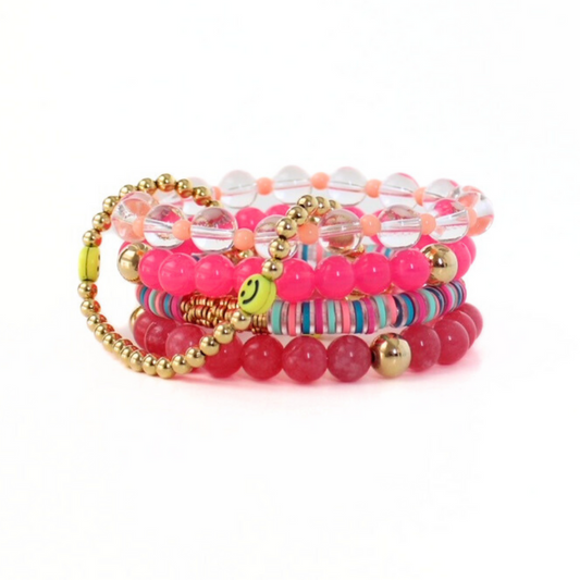5-piece pink beaded bracelet stack. Designed with bright pink acrylic round beads accented with gold filled round beads. Clear quartz round beaded bracelet is adorned wth 4mm peach acrylic beads. Rainbow polymer clay beads and a gold and smiley face beaded bracelet add a playful side.