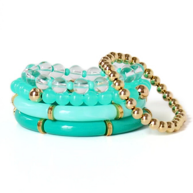 Bracelet stack with five bracelets. 2 bracelets are green bangles with gold plated flats. The third bracelet is an acrylic bracelet with gold filled beads. A clear quartz bracelet with green 4mm acrylic beads and a gold filled beaded bracelet complete the stack.