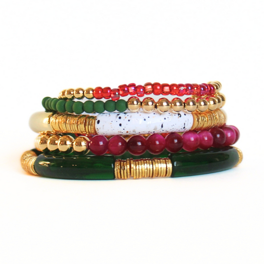 Red and green 5-piece 18K gold beaded stretch bracelet set designed with glass beads, red seed beads and natural fuchsia Tigers eye beads. Two bracelets are designed with white speckled and green acrylic bangles with gold flat beads.