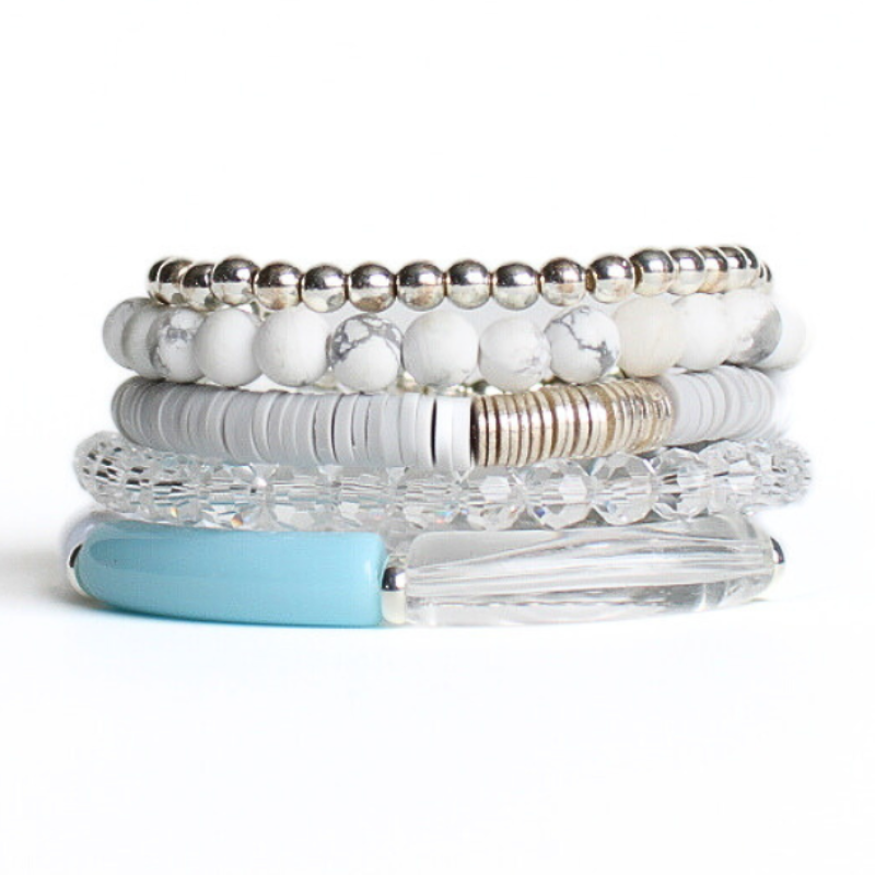 This 5-piece blue and white beaded stretch bracelet set is the perfect statement piece. With its bold neutral colors, it is designed with silver beads, clear glass beads and white howlite beads. The gray polymer clay beads are a playful addition