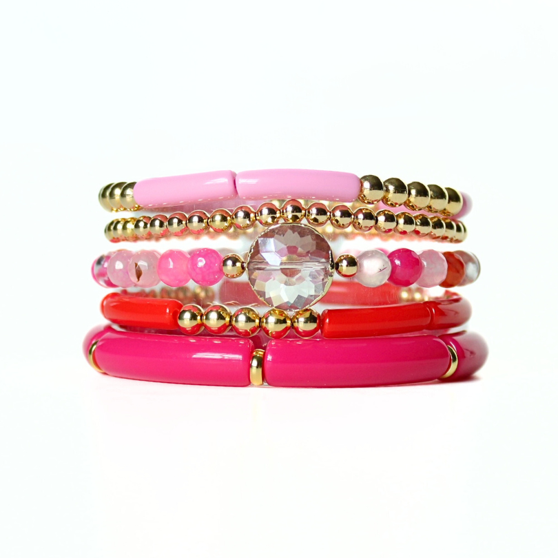 Red and pink bracelet set designed with gold beads, acrylic, and crystal beads.