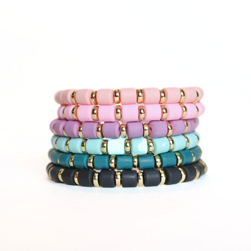 Stack of a variety of colored wide beaded polymer clay beads.  Each designed with alternating gold-plated wide flats.