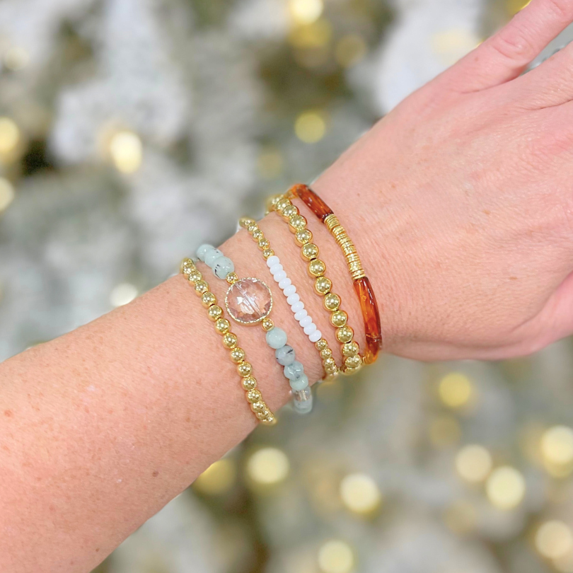 Gold beaded bracelet stack featuring gemstone beads and acrylic beads